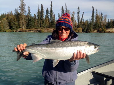 Angler holding a bright Steelhead with river view