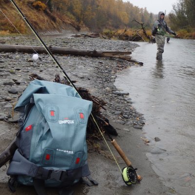 Pack and fly rod with angler fishing a river
